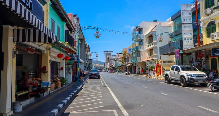 Des maisons-boutiques sino-portugaises colorées bordent une rue tranquille de la vieille ville de Phuket sous un ciel bleu.