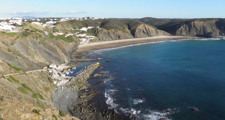 Uitzicht op een strand met kliffen en een witgekalkt dorp langs de kust.