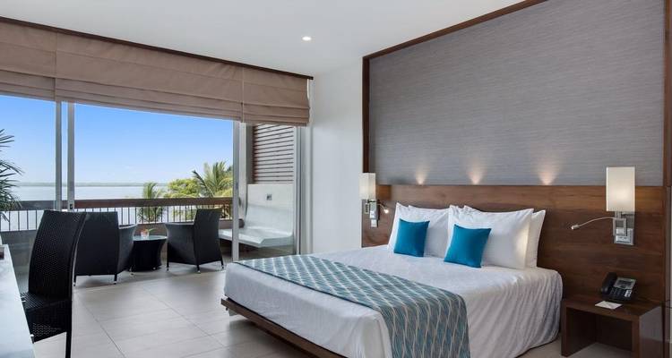 Ein modernes Hotelzimmer mit Blick auf Palmen und einem Balkon.