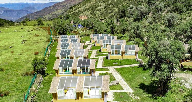 Serie milieuvriendelijke lodges met glazen daken in een bergachtig gebied.