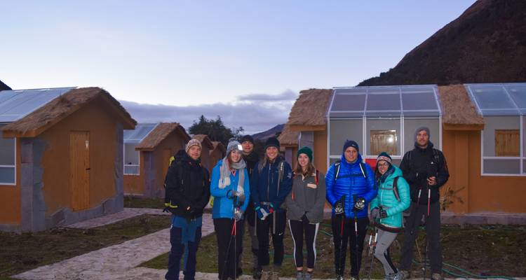 Groep wandelaars voor lodges in een bergachtig gebied.