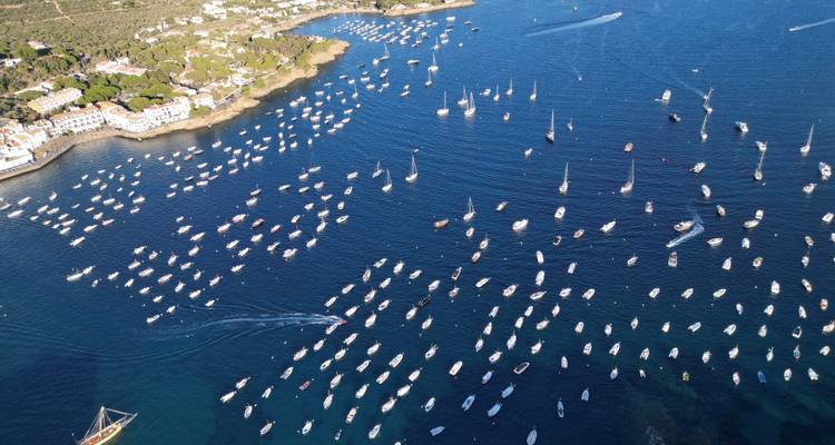 Luchtfoto van honderden zeilboten voor anker in helder blauwe Middellandse Zeewateren dicht bij een kustplaats.
