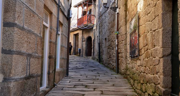 Eine schmale Kopfsteinpflastergasse zwischen historischen Steingebäuden mit einer Person im Blick.