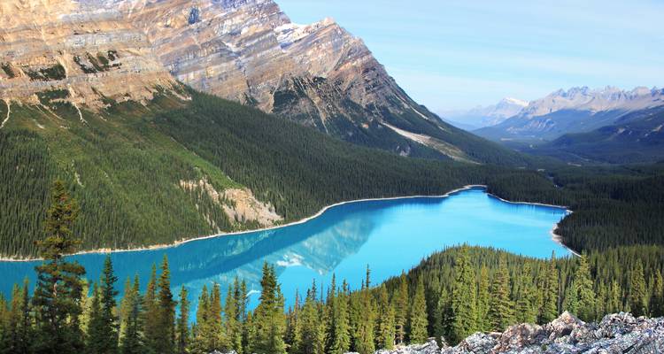 Serene lake in a mountain valley with lush forests.