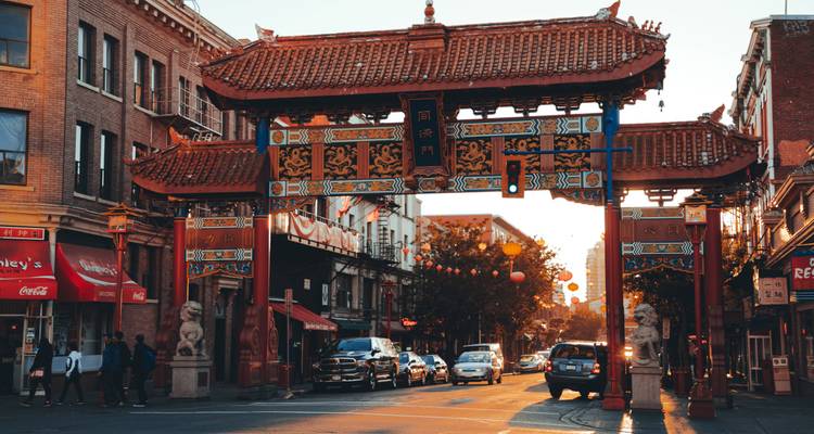 Bustling city street with a traditional Chinese gate under sunset lighting.