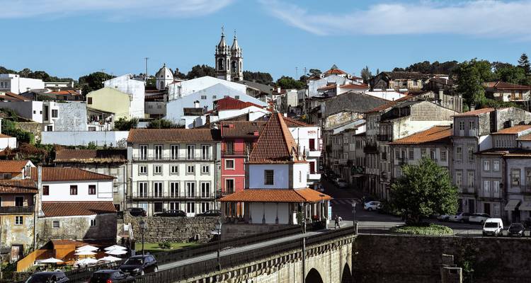 Townscape featuring a distinctive turreted house and surrounding buildings viewed from a historic bridge.