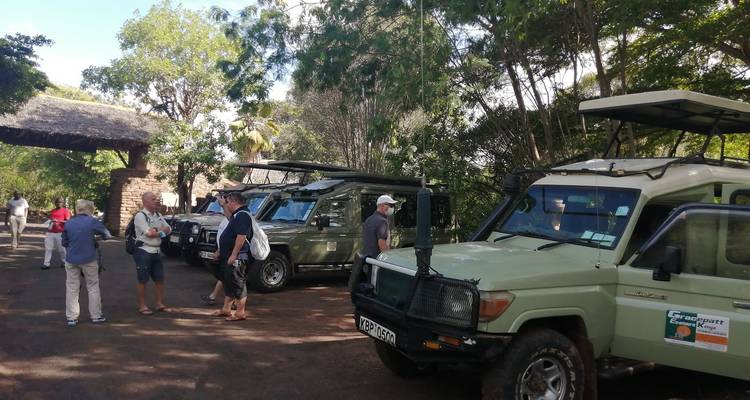 Touristen versammeln sich in der Nähe geparkter Safari-Fahrzeuge.
