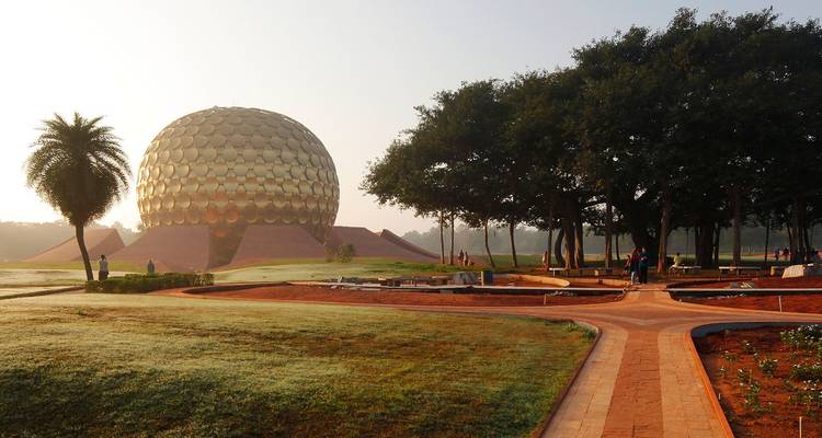 Une structure sphérique dorée au milieu d'un jardin paysager.