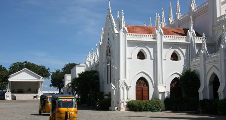 Eine große weiße Kirche mit Tuk-Tuks, die davor geparkt sind.
