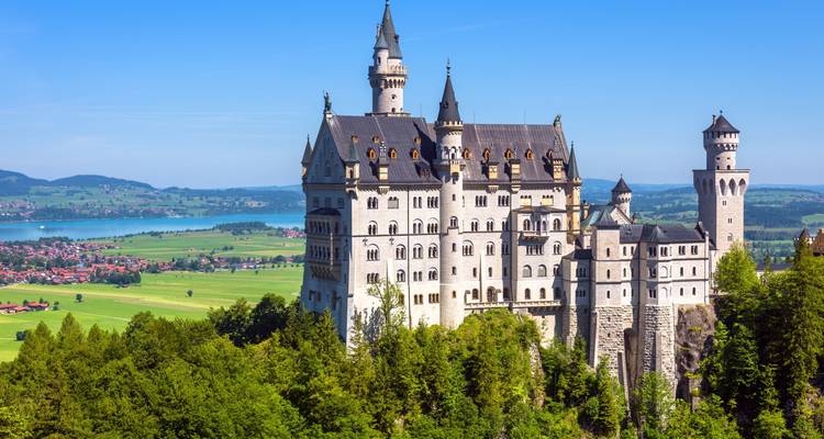 Château de Neuschwanstein avec montagnes et lac en arrière-plan.