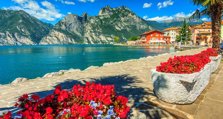Eine malerische Seepromenade mit farbenfrohen Blumen und Bergen.