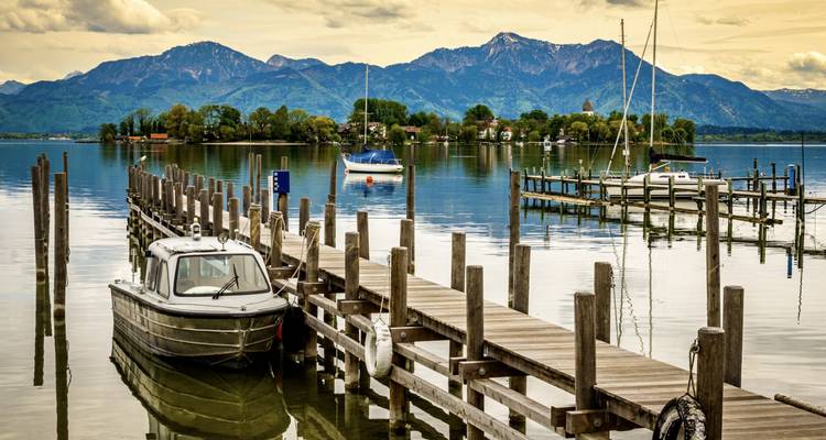Wooden dock with boats on a calm lake with mountains.