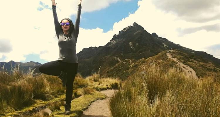 Person doing yoga on a trail with a mountain backdrop.