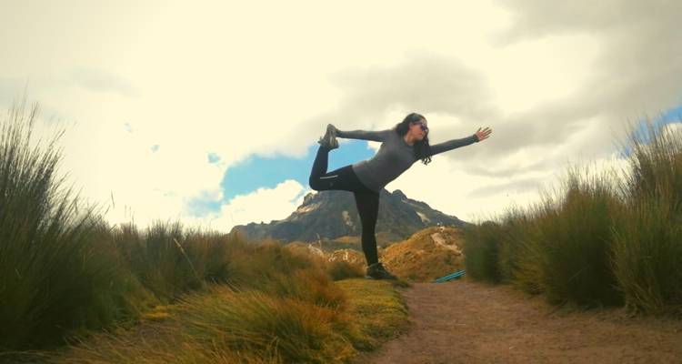 Person doing yoga on a path with mountains in background.