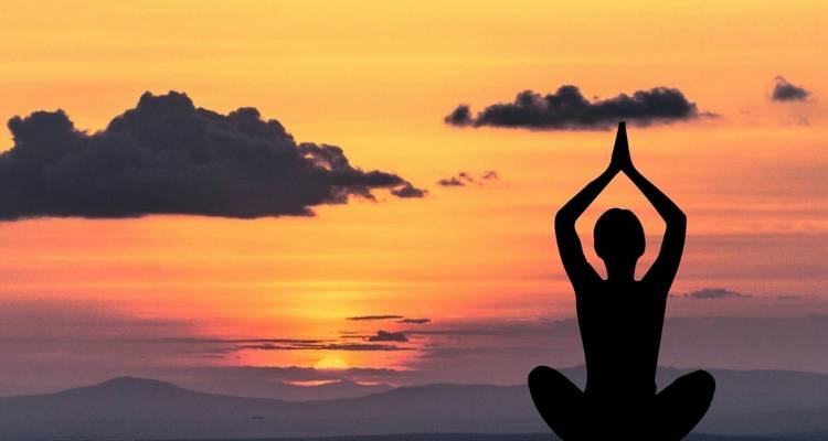 Silhouette of a person meditating at sunset.