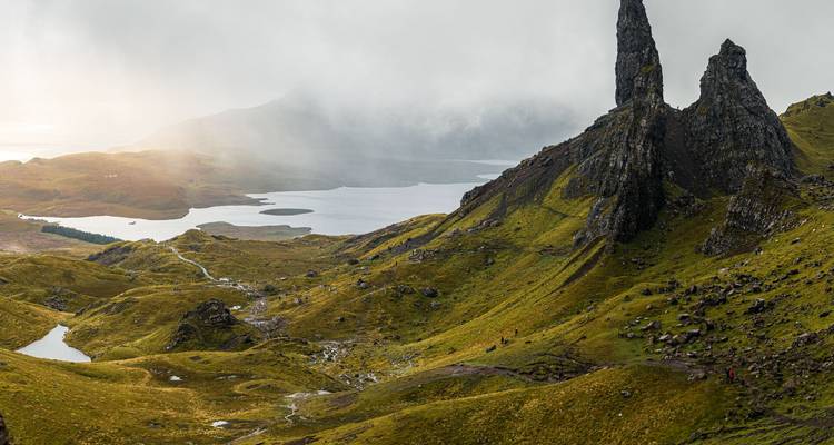 Nebliger Sonnenaufgang über den zerklüfteten Gipfeln des Old Man of Storr mit Blick auf Seen und die sanft hügelige grüne Landschaft von Skye.