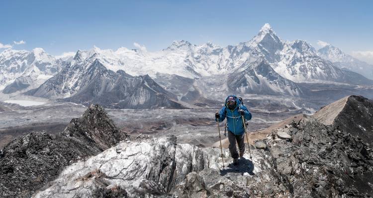 Wandelaar die een besneeuwde bergkam beklimt met een panoramisch uitzicht op de bergen.