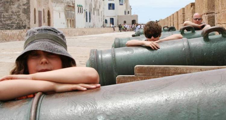 Kinder, die sich an Kanonen entlang einer Stadtmauer anlehnen.