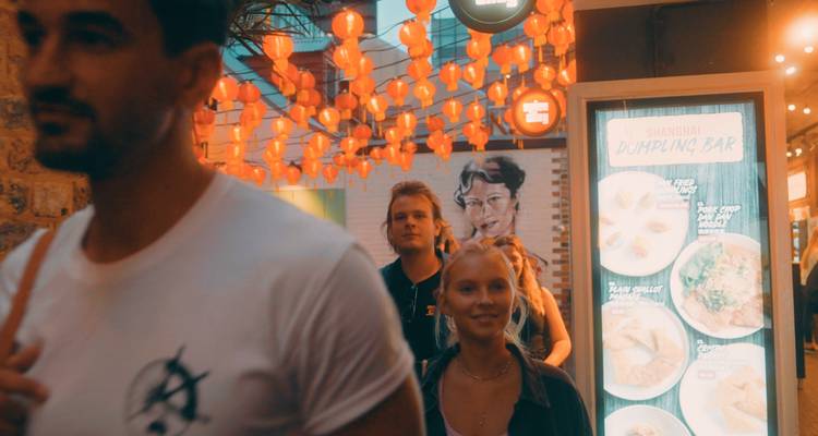 People walking past a dumpling bar.