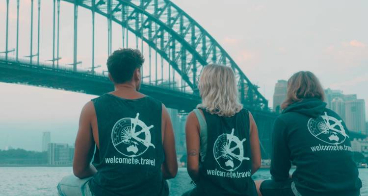Trois personnes assises devant le pont du port de Sydney.