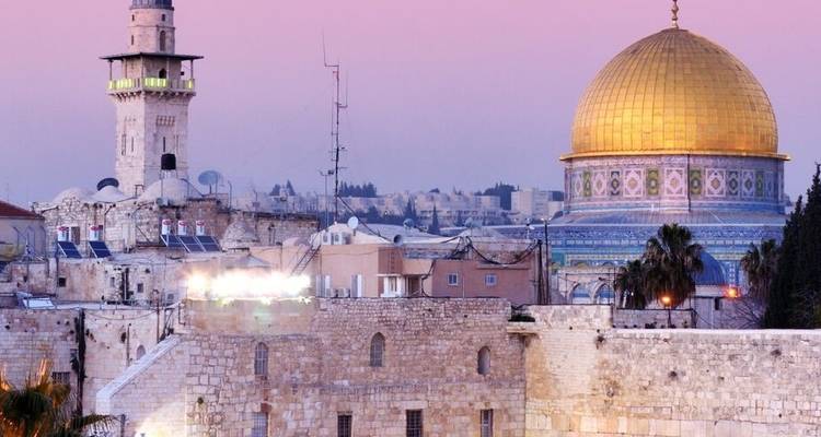 Skyline met een prominente gouden koepel en minaretten bij schemering.