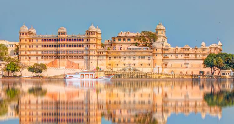 El Palacio de la Ciudad de Udaipur se refleja perfectamente en las tranquilas aguas del Lago Pichola bajo un cielo despejado.