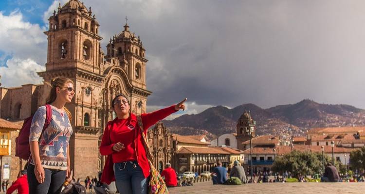 Two people in a plaza with colonial architecture in the background