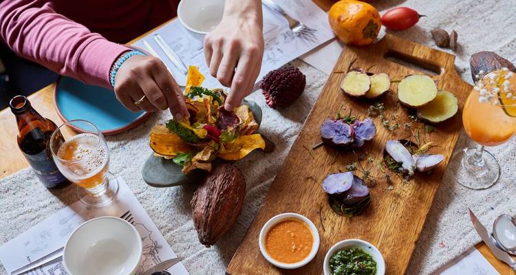A table with traditional Peruvian dishes and someone reaching for food.