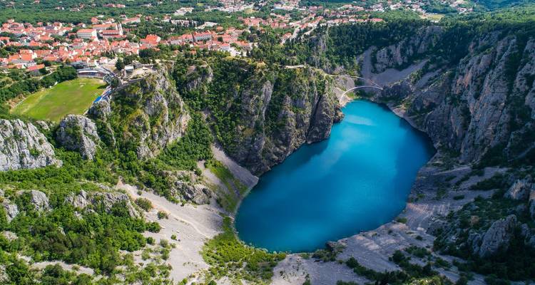 Dramatische luchtfoto van een levendig blauwe dolina-meer omgeven door steile rotsachtige kliffen in Kroatië