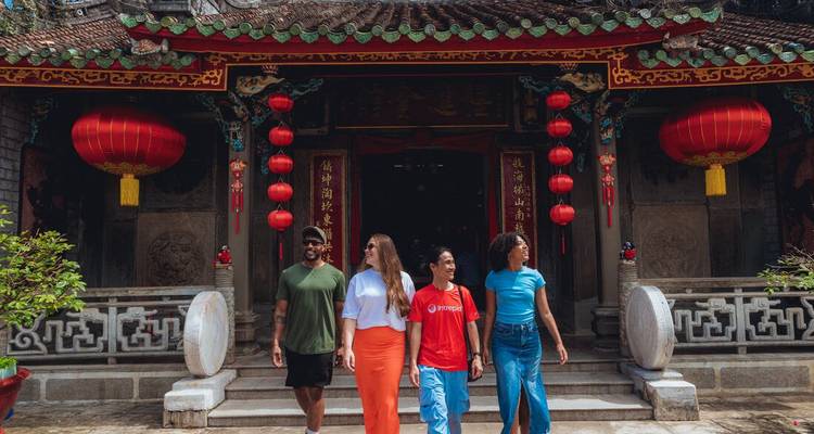 Amigos paseando afuera de un ornado templo chino adornado con faroles rojos