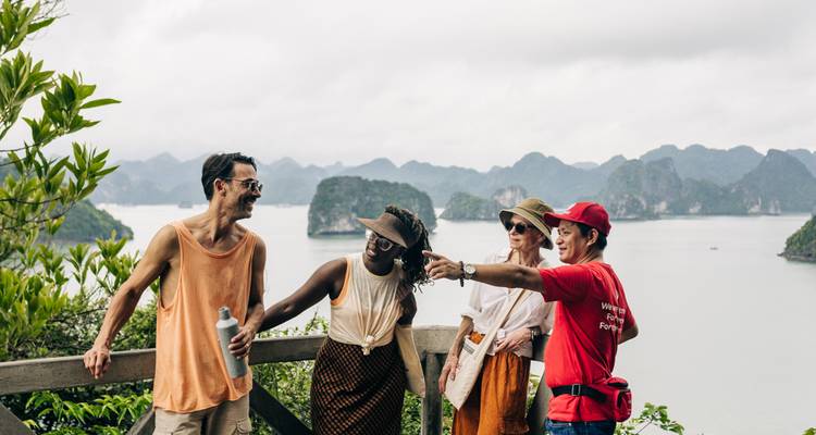 Grupo de turistas observando las islas de piedra caliza envueltas en niebla de la Bahía de Halong