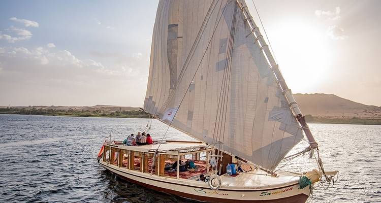 Segelboot auf einem Fluss bei Sonnenuntergang.