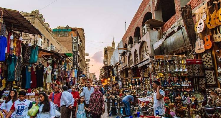 Belebte Marktstraße mit verschiedenen Waren und Menschen.