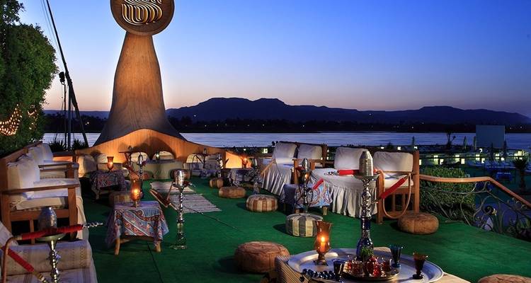 Outdoor terrace at dusk with hookahs and seating.