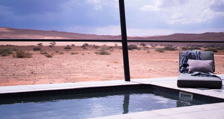 Private plunge pool of a desert lodge overlooking vast arid plains under moody sky