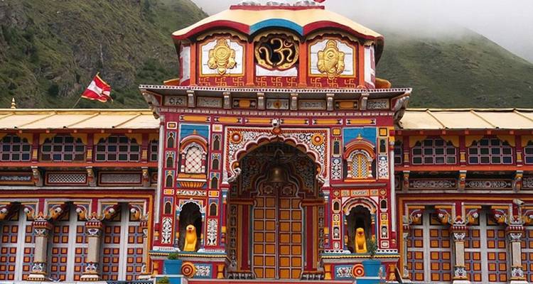 Kleurrijke tempel met bergen die oprijzen op de achtergrond.