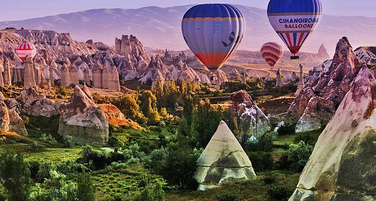 Heißluftballons schweben über Felsformationen.