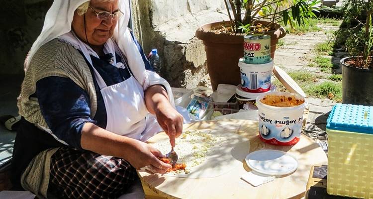 Frau bereitet traditionelles Essen im Freien zu.
