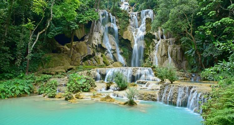 Kaskadende Wasserfälle, die in türkisfarbene Becken fließen, umgeben von üppigem Grün.