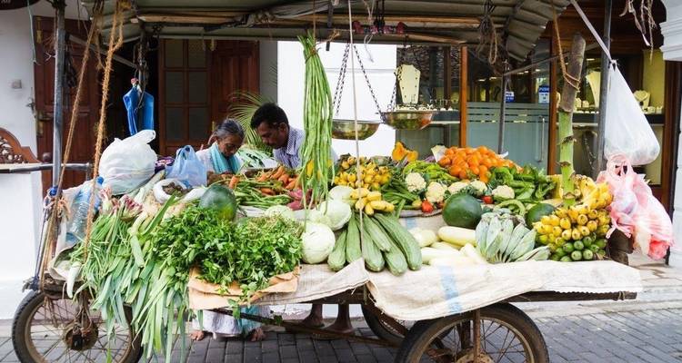 Escena de mercado con carrito de verduras.