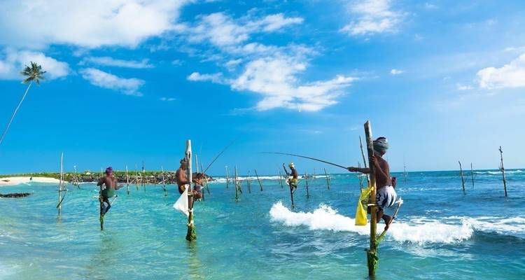 Pescadores en zancos equilibrándose en el océano.