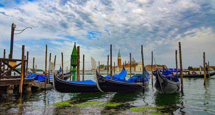 Gondeln liegen in Venedig vor Anker bei bewölktem Himmel.