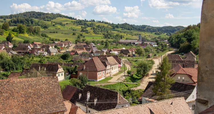 Vue d'un village rural entouré par une campagne verdoyante.