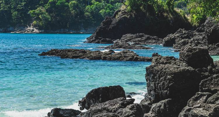 Rotsachtige kustlijn met helderblauwe wateren en weelderig groen.