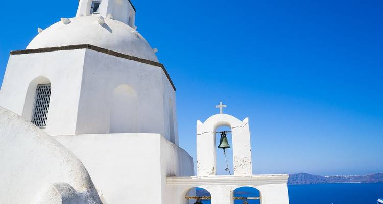 Una iglesia tradicional de cúpula blanca con vista al mar.
