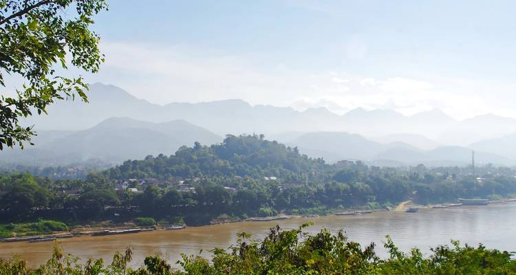 Quiet riverside village with mountains in the background.
**French translation:**
Paisible village au bord de la rivière avec des montagnes en arrière-plan.