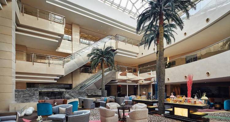 Elegante Hotellobby mit Palmen und luxuriösen Sitzgelegenheiten.