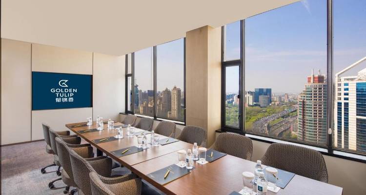 Hotelbesprechungsraum mit einem langen Tisch mit Blick auf eine Stadtlandschaft.