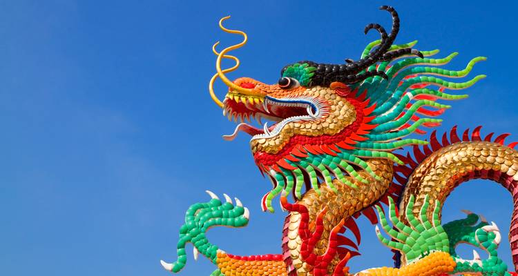 Escultura de dragón colorida contra un cielo azul despejado.