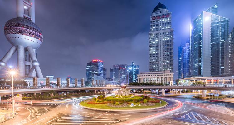 Paisaje urbano de Shanghái de noche con arquitectura moderna y estelas de luz del tráfico.